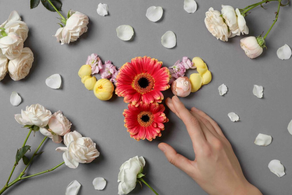 Floral representation of a female reproductive system with hand touch, symbolizing menopause and women’s health transition.