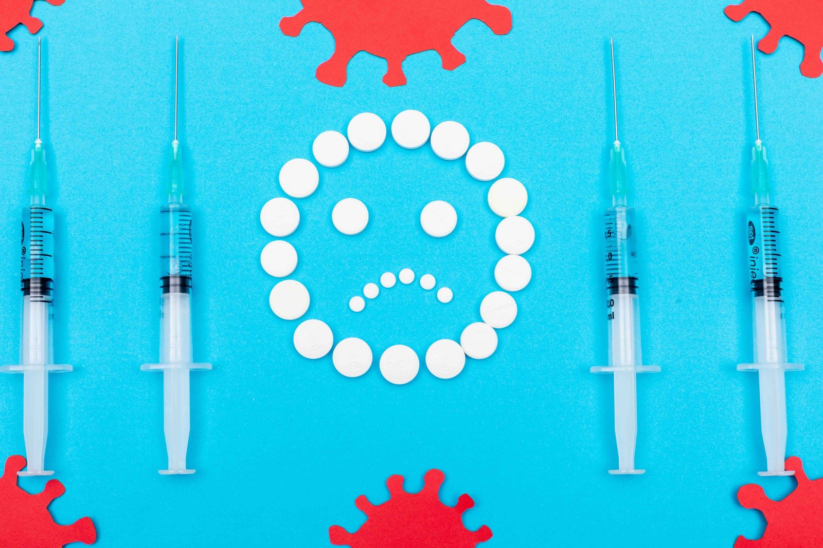 Sad face made of white pills surrounded by syringes and virus symbols, representing the emotional and medical burden of chronic disease.
